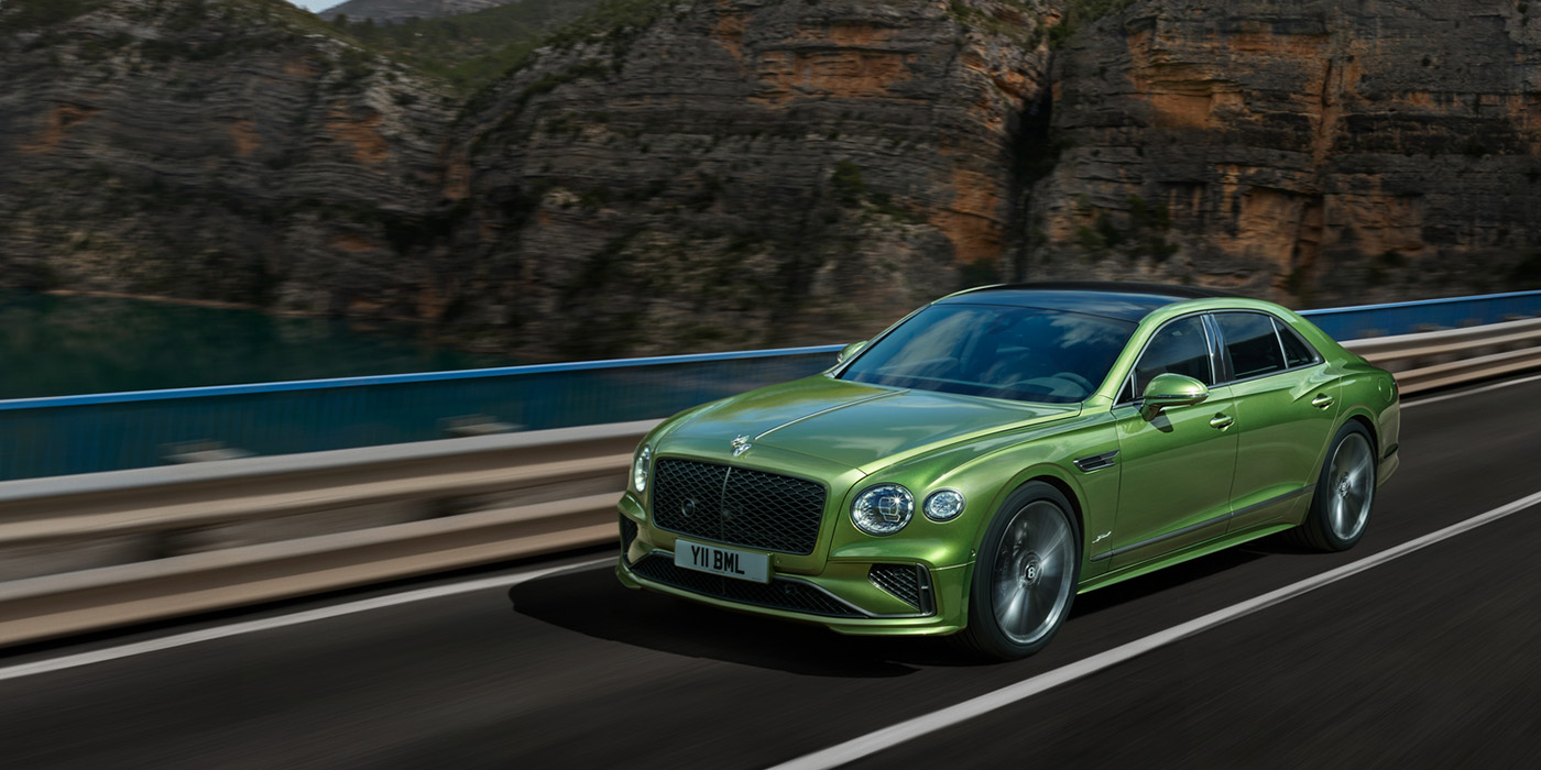 Bentley Almaty Bentley New Flying Spur Speed v8 hybrid sedan driving dynamically on a mountain road in Tourmaline Green paint