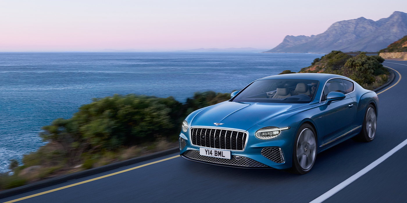 Bentley Almaty New Bentley Continental GT Azure coupe in Light Windsor blue paint with 22 inch Azure wheels and chrome grill, driving dynamically by the sea