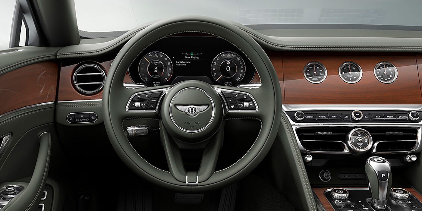 Bentley Almaty New Bentley Flying Spur sedan front cabin in Cumbrian Green hide and Crown Cut walnut veneer showing steering wheel and Rotating Display with three clocks on face