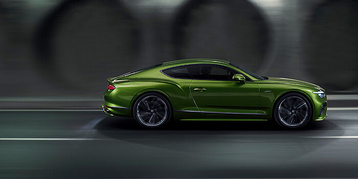 Bentley Almaty Bentley Continental GT coupe in Tourmaline Green paint driving in profile on a dark road
