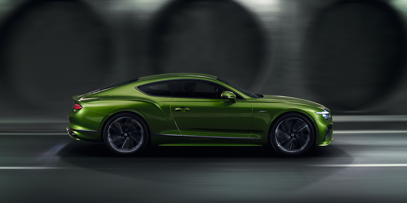Bentley Almaty Bentley Continental GT coupe in Tourmaline Green paint driving in profile on a dark road