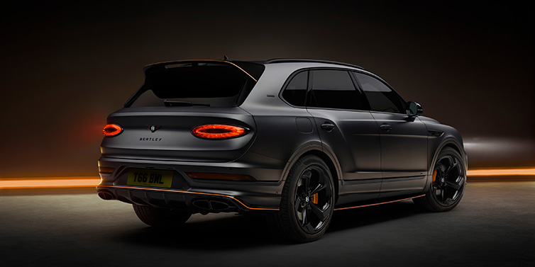 Bentley Almaty Bentley Bentayga S Black Edition SUV rear three quarter in Anthracite Satin paint against a dark red and yellow background