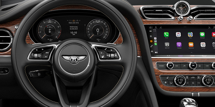 Bentley Almaty Bentley Bentayga SUV front interior detail of steering wheel and driver screens surrounded by Beluga black hide and Crown Cut Walnut veneer